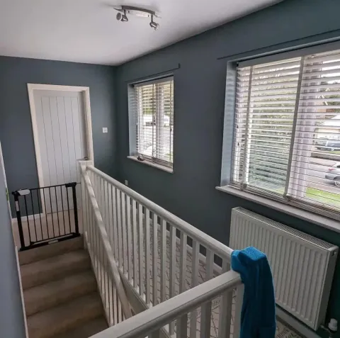 Freshly painted upstairs landing in a deep slate blue with white trim, spindles and doors
